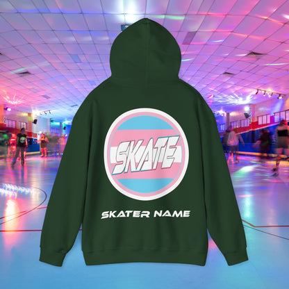 A person wearing a Printify "Add Custom Name - SKATE Trans Flag round logo Hoodie - Australian Shipping," a black unisex heavy blend hooded sweatshirt featuring the word "SKATE" inside a trans circle logo on the back with their skater name written beneath it. The background shows an indoor roller skating rink with colorful lights and other skaters.