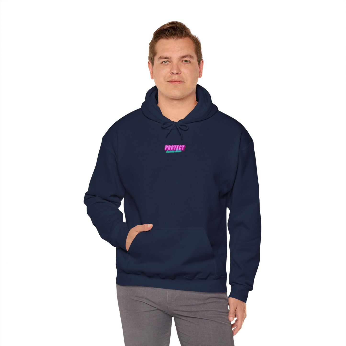 A person is standing against a plain white background, wearing the "Protect Trans Kids" hoodie in navy, made from ethically grown cotton. The hoodie has a small pattern that says "PROTECT" in pink letters on the front and is paired with gray pants. One hand rests in the pocket of the unisex hoodie.