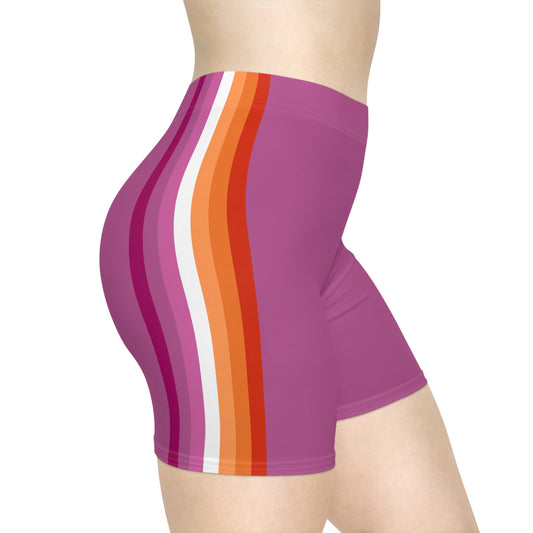 A person is wearing the Printify Lesbian Pride Flag Bike Shorts, made from moisture-wicking fabric and featuring a pink base color with vertical stripes in red, orange, and white on the side. The photo captures a side profile from the waist to mid-thigh.