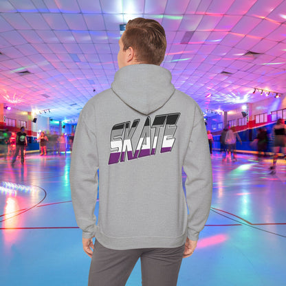 A person wearing a Printify SKATE Asexual Pride Hoodie, featuring the word "SKATE" printed on the back in gradient colors, stands in a brightly lit roller skating rink, observing the skaters. The rink is illuminated with colorful lights and exudes a lively atmosphere.