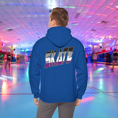 A person wearing a Printify SKATE Asexual Pride Hoodie, featuring the word "SKATE" printed on the back in gradient colors, stands in a brightly lit roller skating rink, observing the skaters. The rink is illuminated with colorful lights and exudes a lively atmosphere.