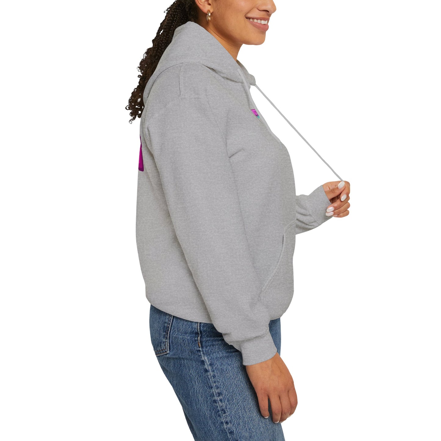 A person smiles from the side, wearing a Protect Trans Kids Hoodie - Australian Shipping in gray made from ethically grown cotton, paired with blue jeans. They have long curly hair pulled back and are holding the hood's drawstring.