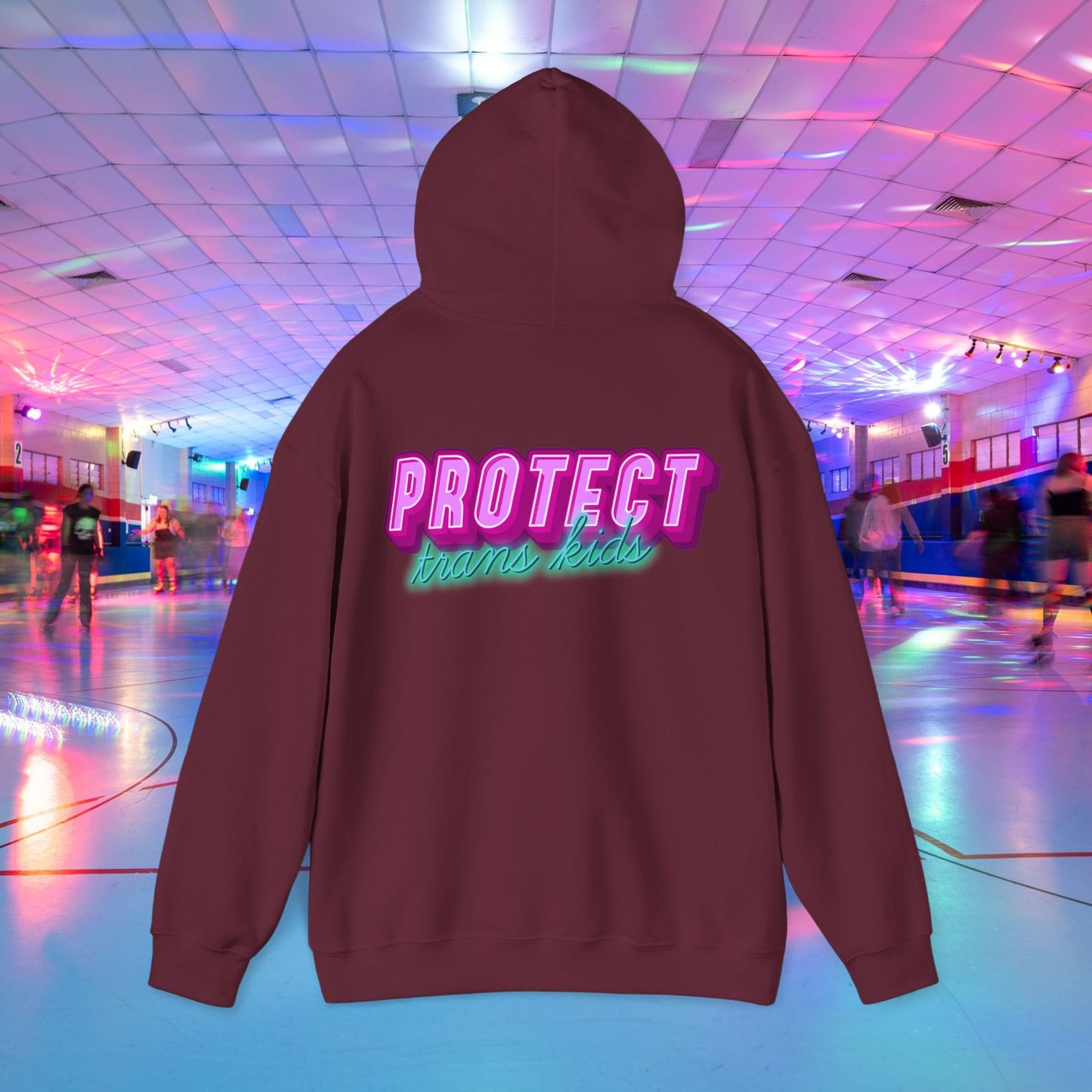 The Protect Trans Kids Hoodie - Australian Shipping is an ethically crafted maroon unisex hoodie featuring the phrase "PROTECT trans kids" in bold, colorful letters. Set against a lively roller skating rink backdrop with vibrant lights and skaters gliding by, it captures an inclusive spirit.