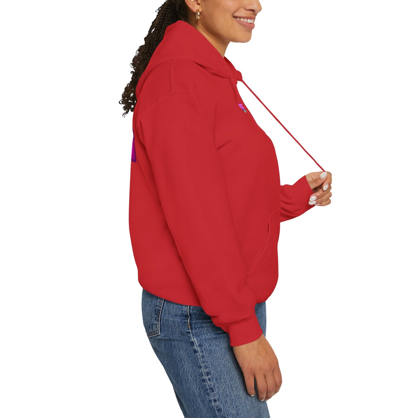 A person in a red "Protect Trans Kids" hoodie and blue jeans stands in profile, smiling while holding one of the hoodie strings against a white background.