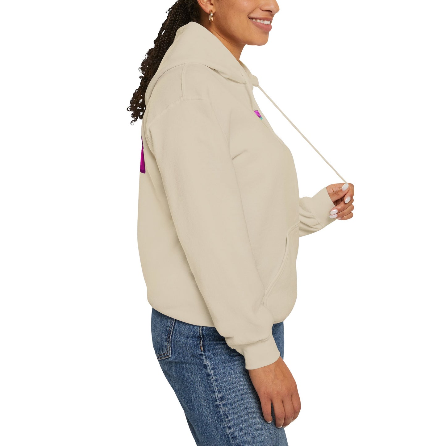 A person wearing a Protect Trans Kids Hoodie - Australian Shipping in beige and blue jeans stands sideways, smiling. This ethically grown cotton hoodie has a front pocket and drawstrings, perfect for any wardrobe. Their long, curly hair contrasts beautifully against the white background.