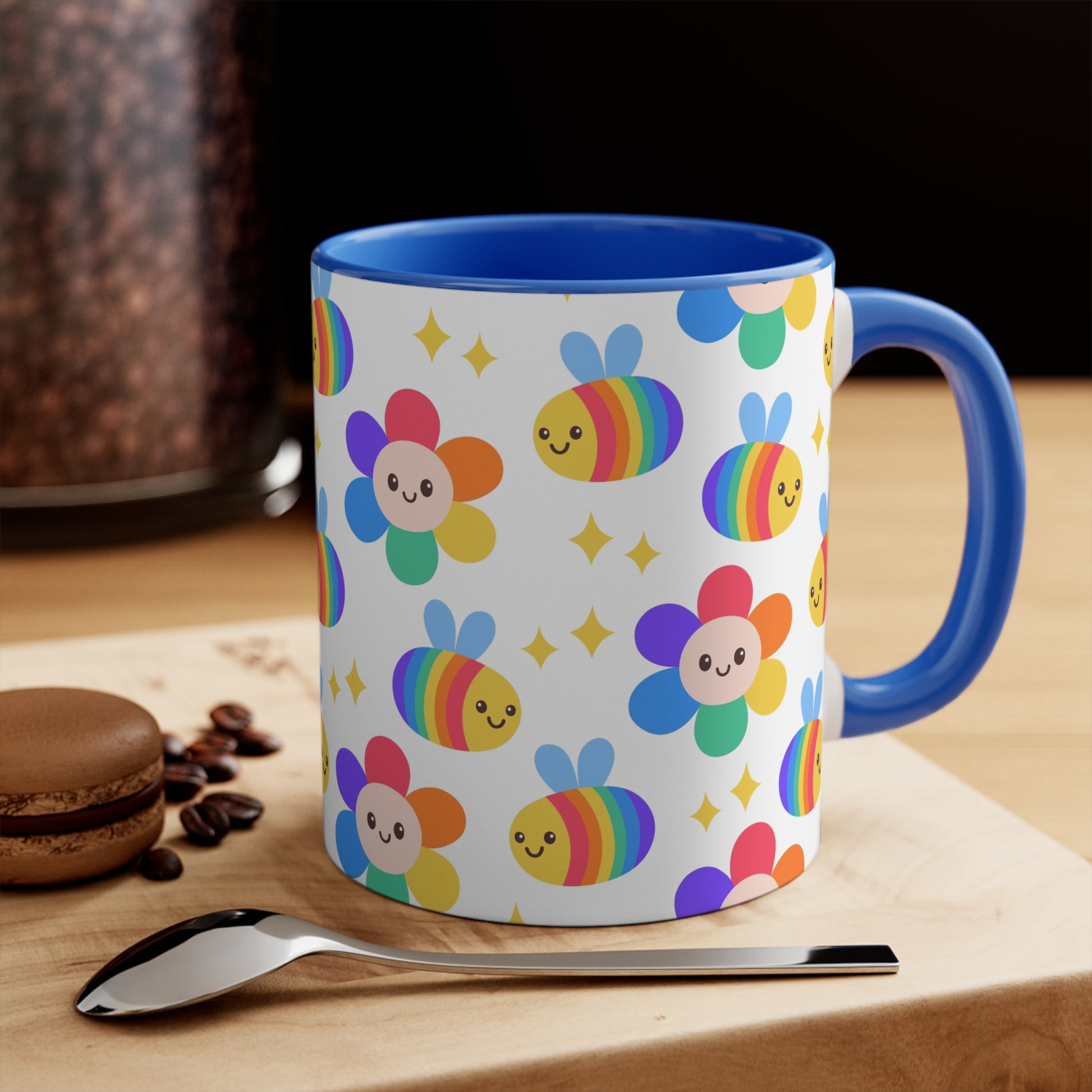 The Subtle Rainbow Pride - Flowers and Bees Colourful Accent Mug by Printify is a white ceramic mug with a red handle and colored interior, adorned with a vibrant pattern of adorable smiling bees and flower designs. The cheerful bees and flowers are rendered in bright rainbow colors reminiscent of the pride flag, with small yellow stars scattered throughout.