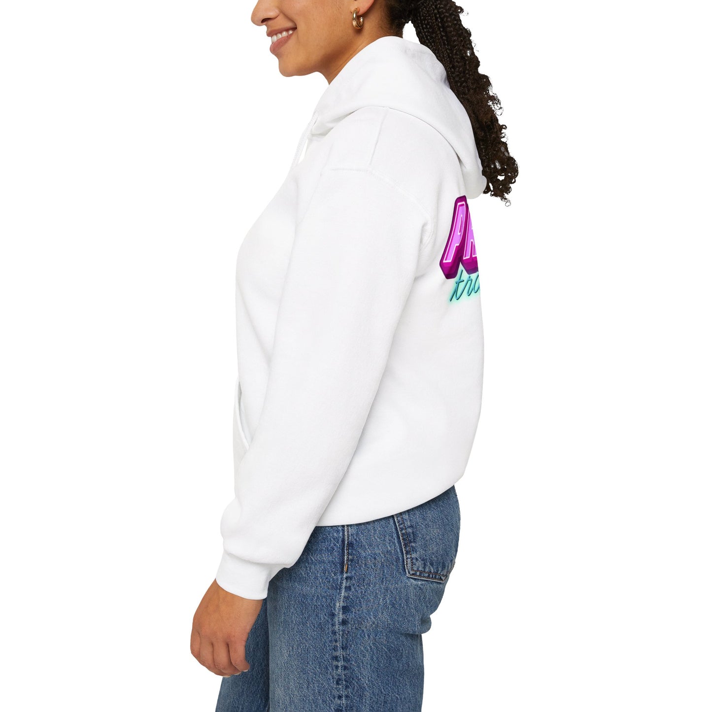 A person wearing the "Protect Trans Kids Hoodie - Australian Shipping" made from ethically grown cotton stands sideways, smiling. The white hoodie features colorful text on the back. They have curly hair and blue jeans, set against a plain white background.