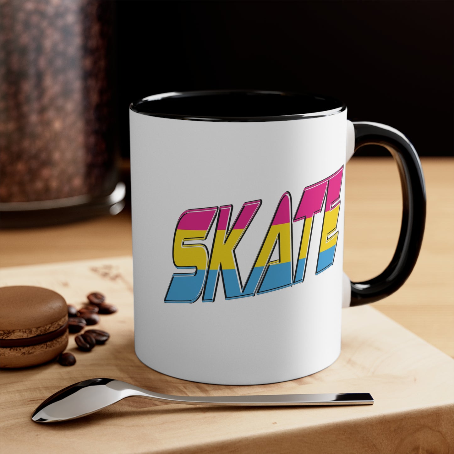 Introducing the "SKATE pansexual pride flag accent mug" by Printify—a white ceramic coffee mug highlighted with a black handle and interior. Adorned on the front are bold, colorful letters spelling "SKATE," featuring a gradient effect in pink, yellow, and blue that beautifully represents the pansexual pride flag.