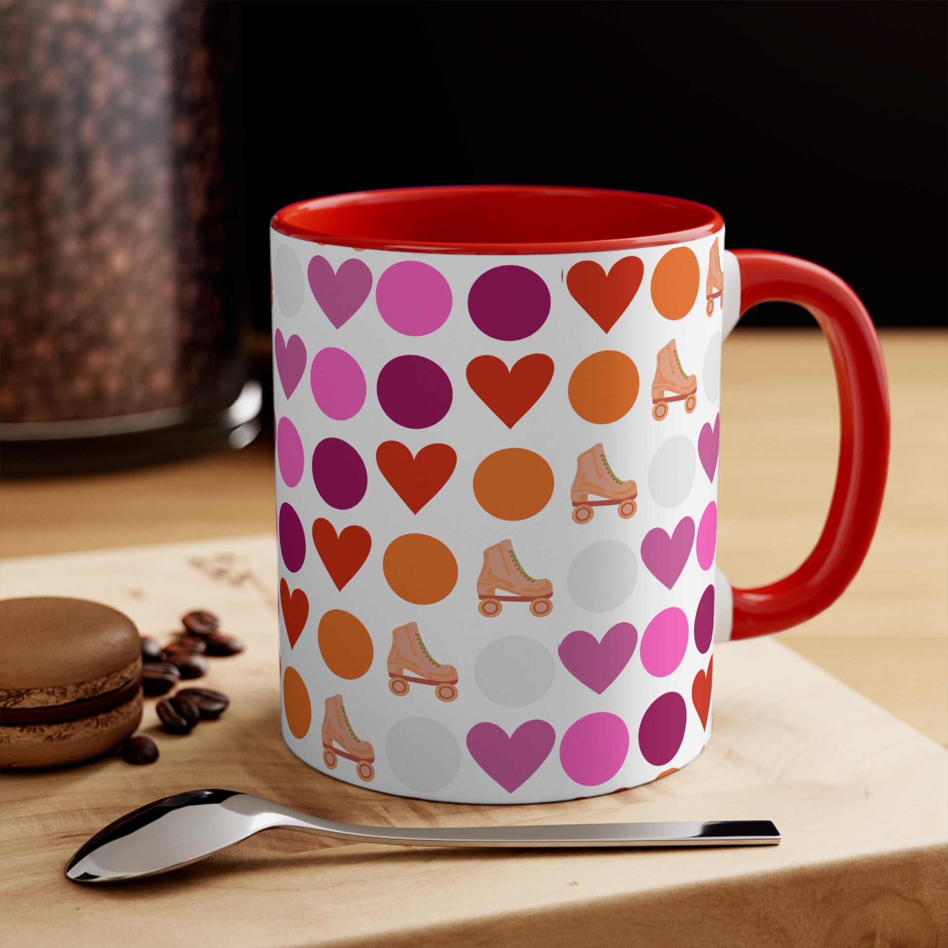 The Subtle Lesbian Pride + Roller Skate Colourful Accent Mug by Printify is a white ceramic mug featuring a red handle and a vibrant interior. It is adorned with a playful pattern of hearts, circles, and roller skates in an array of colors, including pink, purple, orange, and red.