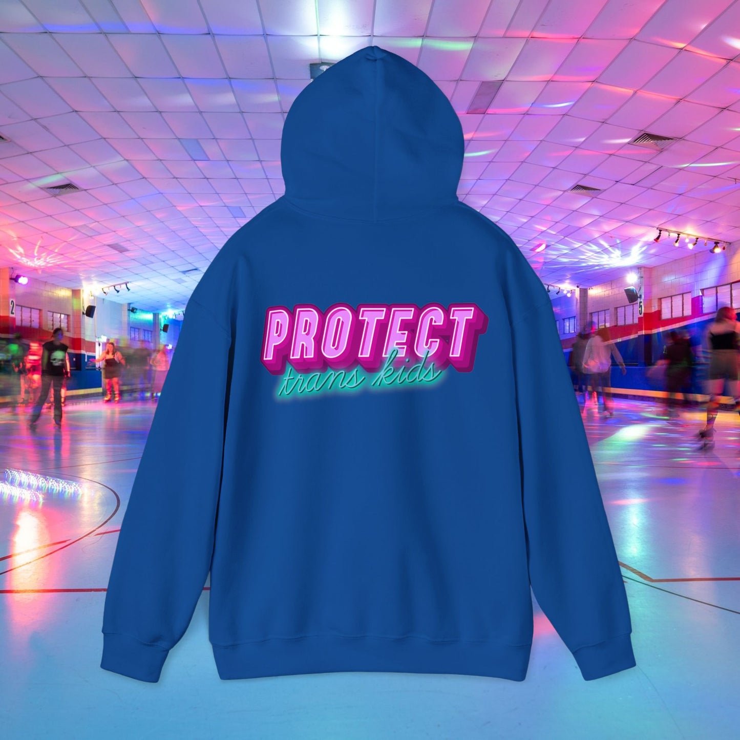 The "Protect Trans Kids Hoodie" with bold lettering on the back, available for Australian shipping, stands out in a neon-lit roller skating rink. It's made from ethically grown cotton and offers both comfort and a strong message.