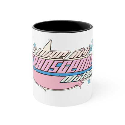 The I Love My Transgender Mother original design accent mug from Printify is a white ceramic mug featuring a pink interior. It displays colorful, stylized text in pink and blue with a 3D effect that reads "I love my transgender mother." The design is highlighted with star motifs and set against a vibrant background.