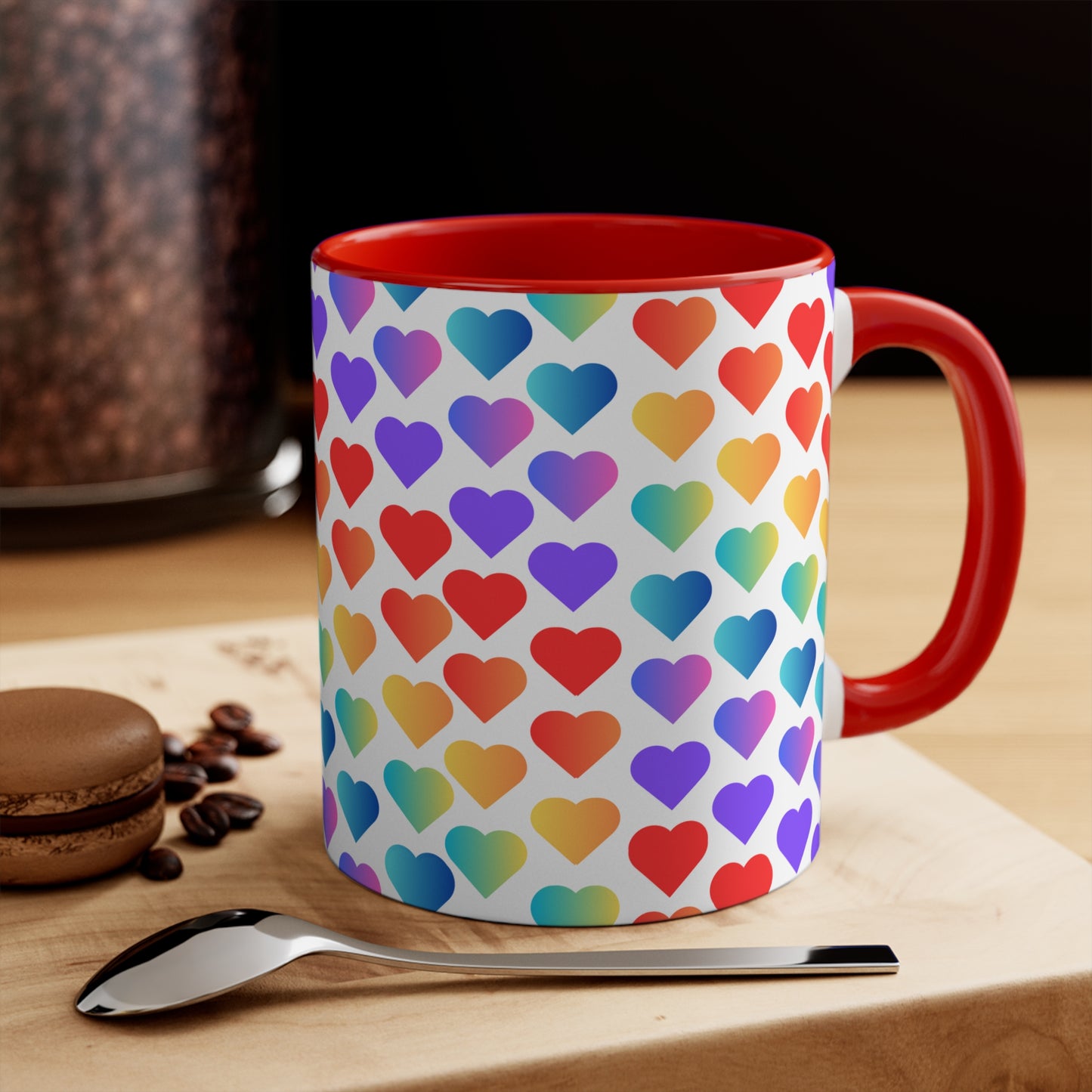 The Rainbow Pride Love Hearts Colorful Accent Mug by Printify is a white mug with a red handle and a colorful interior, adorned with a vibrant pattern of gradient hearts. The hearts transition through various colors, creating an eye-catching color contrast against the white background.