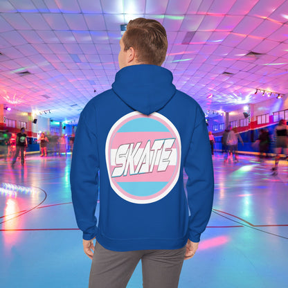 A person wearing a Printify SKATE Trans Flag round logo Hoodie, featuring the word "SKATE" inside a blue and pink circular graphic, stands at the center of a colorful roller skating rink with vibrant lights and other skaters in the background.