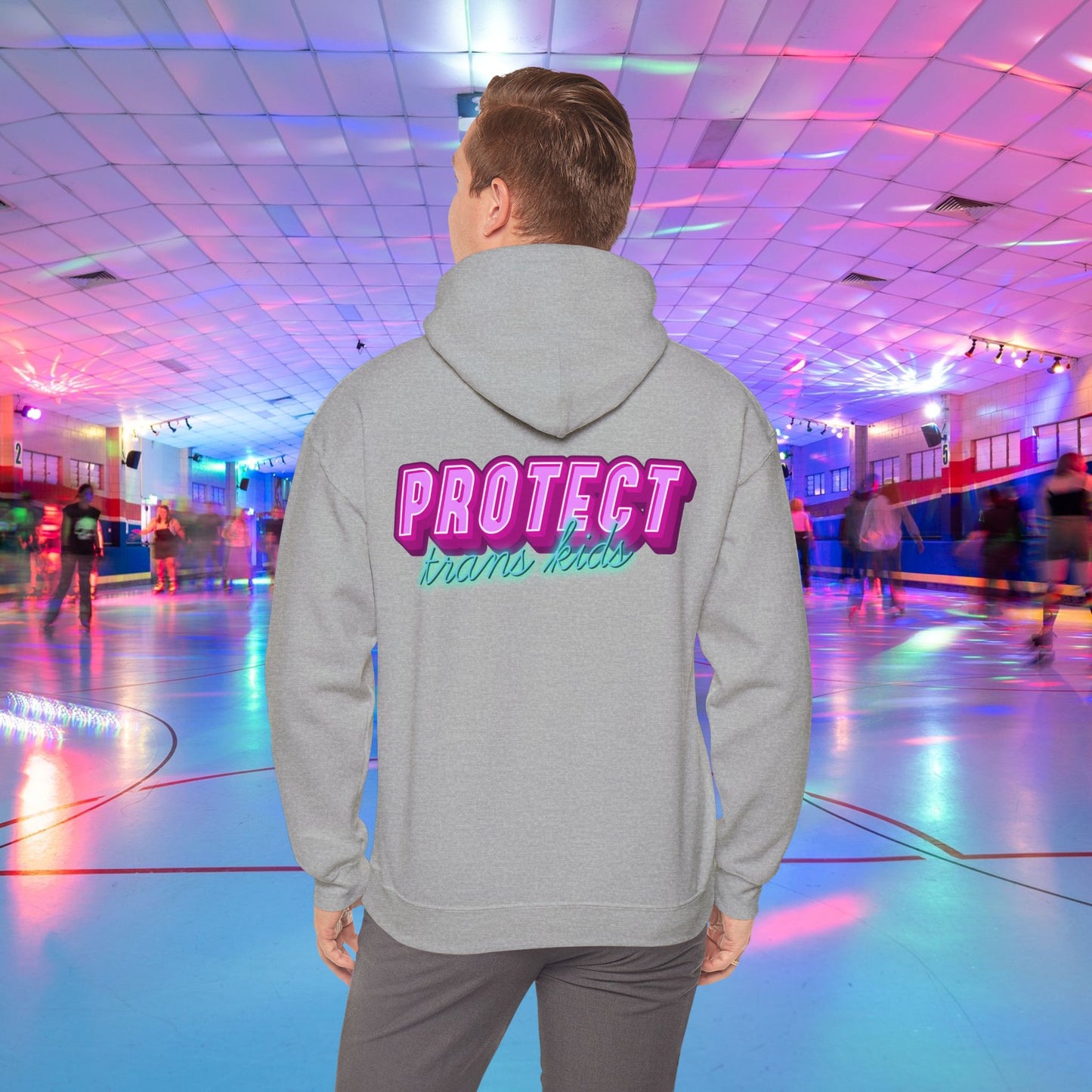 A person in a high-quality Protect Trans Kids Original Hoodie from Printify, crafted from ethically grown cotton, glides effortlessly at a vibrant roller rink illuminated by neon lights. The bold, colorful lettering on their hoodie reads "PROTECT trans kids," while other skaters create a lively, blurred backdrop.