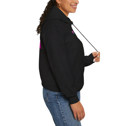 A person in a "Protect Trans Kids Hoodie - Australian Shipping" smiles while slightly facing right. They hold a hoodie string, dressed in blue jeans with curled hair and a friendly expression. The ethically grown cotton adds comfort to their style against the white background.