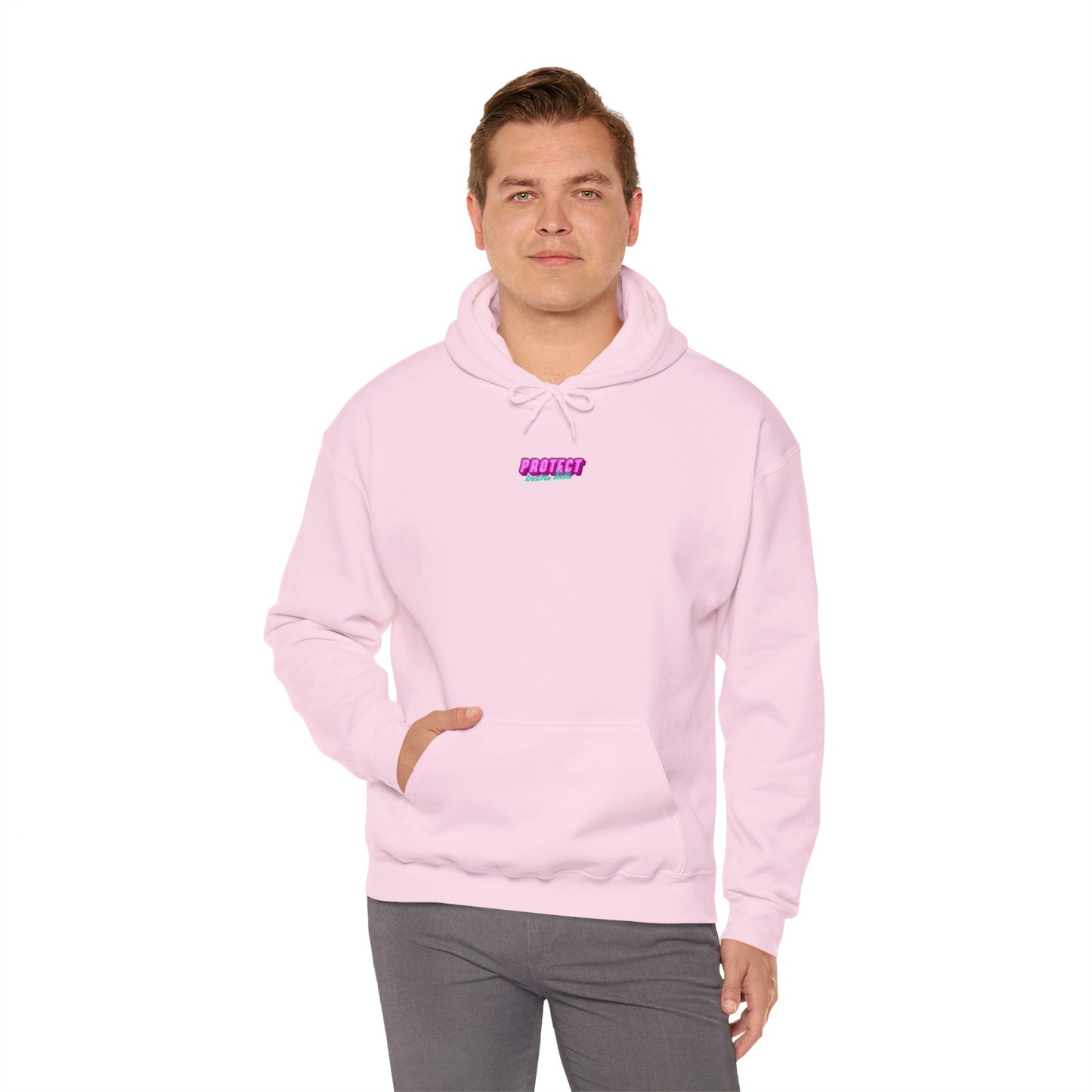 A person in a light pink "Protect Trans Kids" hoodie, made from ethically grown cotton, with a small "PROTEST" graphic on the chest, stands against a plain white background. One hand is in their pocket as they look forward.