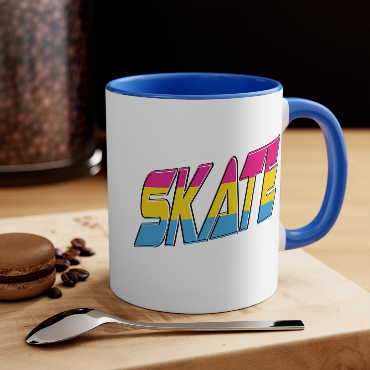 Introducing the "SKATE pansexual pride flag accent mug" by Printify—a white ceramic coffee mug highlighted with a black handle and interior. Adorned on the front are bold, colorful letters spelling "SKATE," featuring a gradient effect in pink, yellow, and blue that beautifully represents the pansexual pride flag.