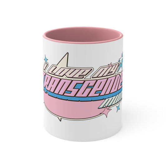 The "I Love My Transgender Mum" original design accent mug by Printify is a white ceramic mug with a vibrant pink interior. It features the stylized word "Transcend," adorned with stars and gradient shades of pink, blue, and purple that represent the colors of the transgender pride flag.