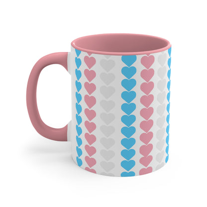 The Trans pride flag love hearts colourful accent mug by Printify features a white exterior adorned with vertical rows of pink, blue, and white hearts, reminiscent of the trans pride flag. Its cheerful and colorful appearance is enhanced by the pink handle and inner rim.