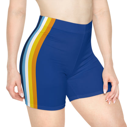 A person wearing Printify's Aroace Pride Flag Bike Shorts, which are high-waisted blue athletic shorts featuring vertical stripes in dark blue, light blue, white, yellow, and orange down the side. The photo captures the lower torso and upper thighs from a side view.