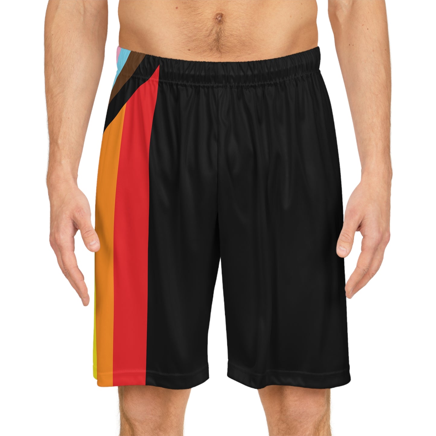 A person is wearing Printify's Progress Pride Rainbow Flag Basketball Shorts made from black, odor-resistant fabric. The shorts feature a vibrant diagonal stripe design in red, orange, yellow, green, blue, brown, black, light blue, pink, and white on the left side. The person's torso is partially visible.