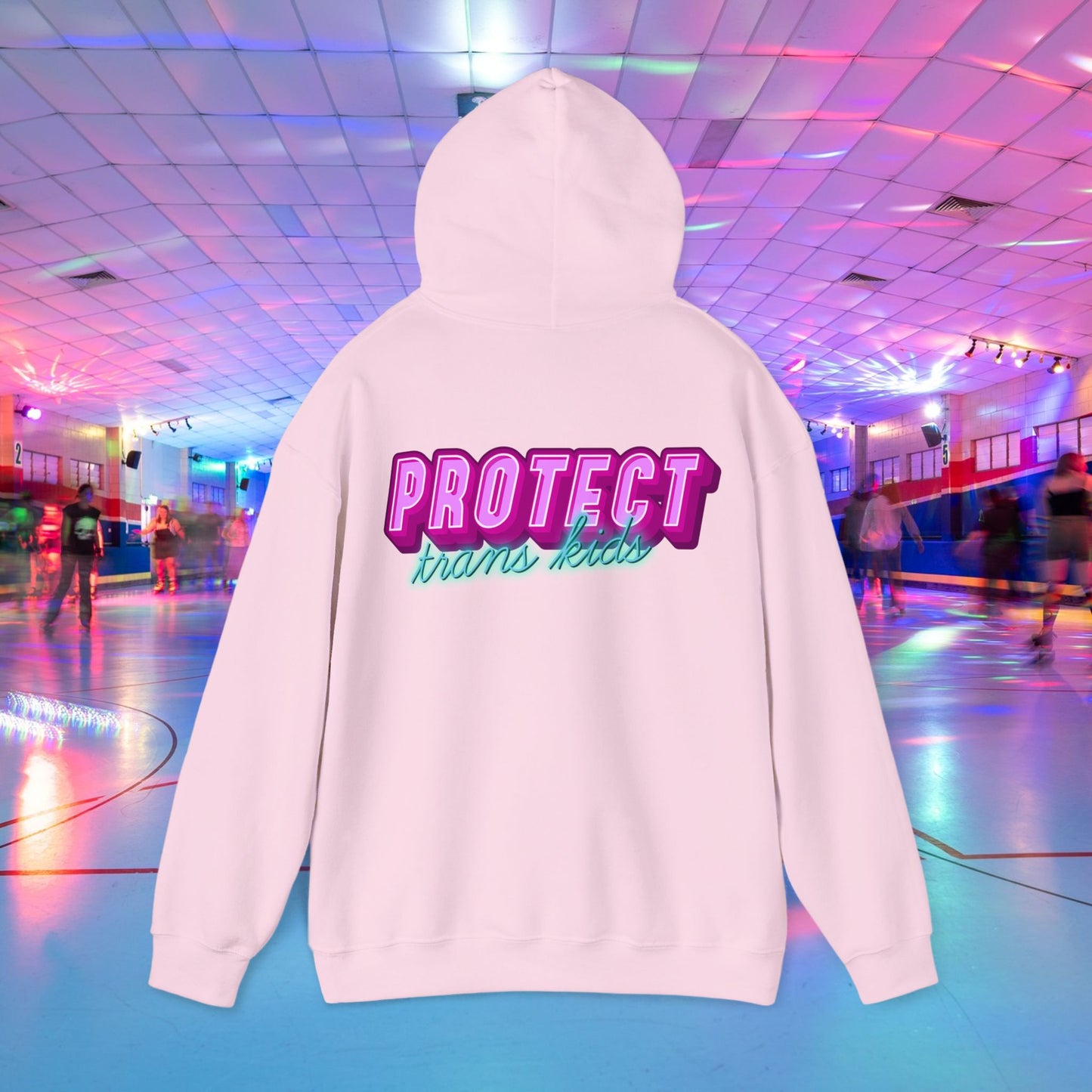 A Protect Trans Kids Hoodie - Australian Shipping steals the spotlight at a roller skating rink. Featuring bold pink and teal "PROTECT trans kids" text on the back, it's crafted from ethically grown cotton and reflects the rink's vibrant, supportive vibe with colorful lights.