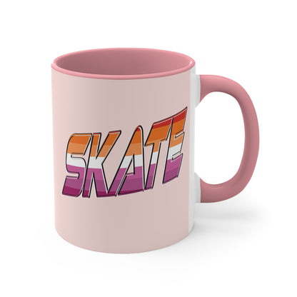 The SKATE lesbian pride flag accent mug by Printify features a bold "SKATE" design in gradient colors of orange, pink, and purple. This eye-catching ceramic mug boasts a light pink handle and interior that beautifully contrast with its pale pink exterior.