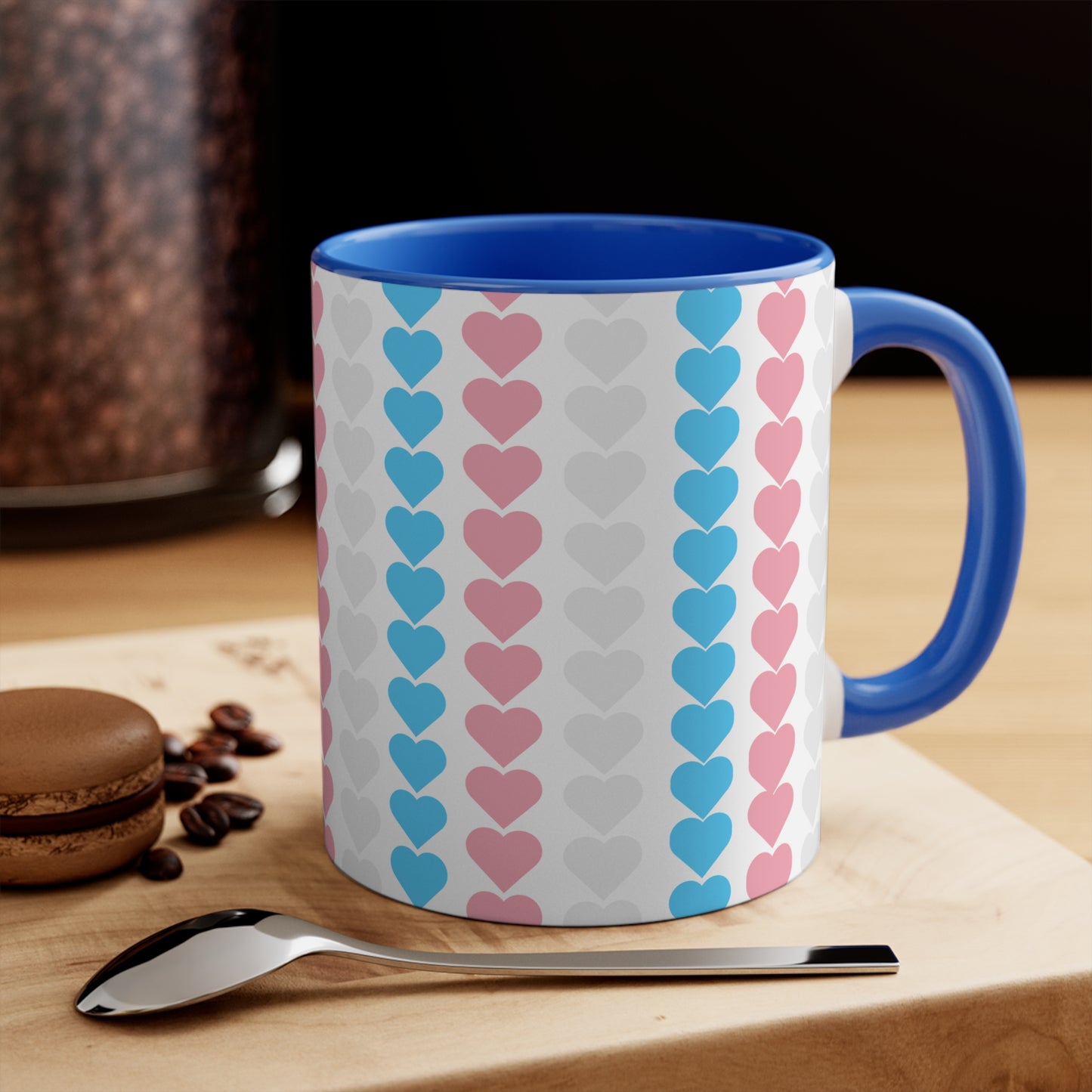 The Trans pride flag love hearts colourful accent mug by Printify features a white exterior adorned with vertical rows of pink, blue, and white hearts, reminiscent of the trans pride flag. Its cheerful and colorful appearance is enhanced by the pink handle and inner rim.