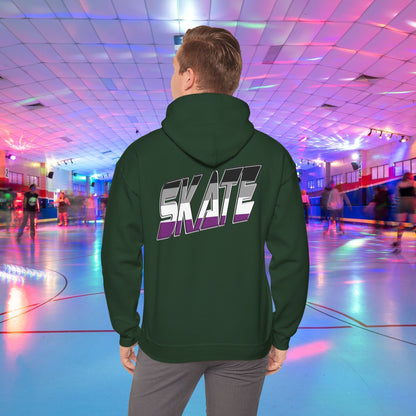 A person wearing a Printify SKATE Asexual Pride Hoodie, featuring the word "SKATE" printed on the back in gradient colors, stands in a brightly lit roller skating rink, observing the skaters. The rink is illuminated with colorful lights and exudes a lively atmosphere.