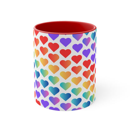 The Rainbow Pride Love Hearts Colorful Accent Mug by Printify is a white mug with a red handle and a colorful interior, adorned with a vibrant pattern of gradient hearts. The hearts transition through various colors, creating an eye-catching color contrast against the white background.