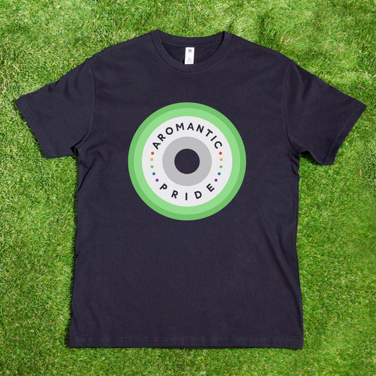 The Aromantic Pride T-shirt by Gay Skate features a striking design of durable prints with concentric circles radiating from a dark center, surrounded by rings in white, light, and dark green. This stylishly black AS Colour T-shirt proudly displays "AROMANTIC PRIDE" and is beautifully presented laid on grass.