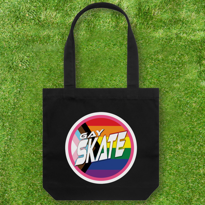 This large black Cotton Canvas Tote Bag from Gay Skate features a vibrant circular "GAY SKATE" logo, representing a queer and trans owned small business. Against a lush green grass background, it serves as both a statement piece and a celebration of bold identity.