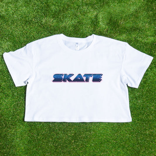 Laid out on a vibrant green grass background is the SKATE blue neon logo crop tee, locally printed by Gay Skate. This standout piece from a trans-owned small business captures the spirit of queer skate streetwear.