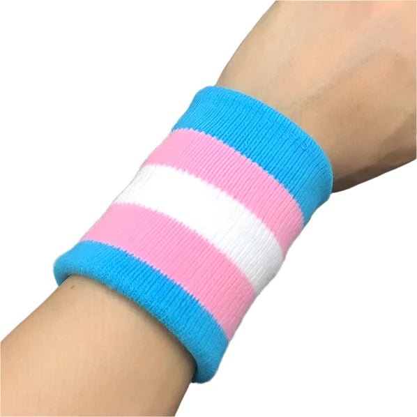 A wrist adorned with the Gay Skate Trans pride flag sporty wrist band featuring horizontal stripes in light blue, pink, and white - the transgender pride flag. An accessory for clubbing, raves, parties and festivals. Perfect for transmen, transgirls, transwomen, non-binary and other genderqueer people.