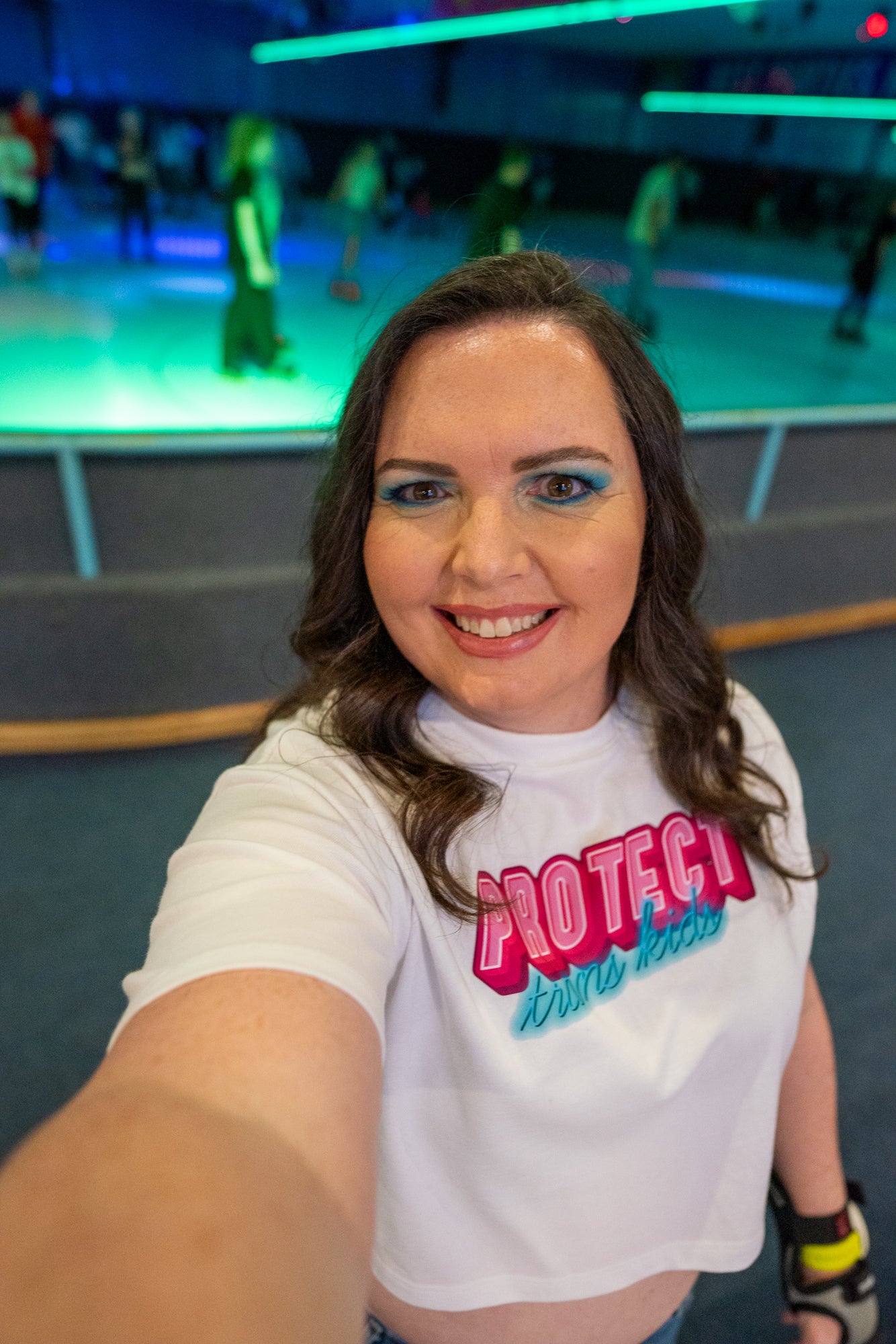 The Gay Skate's "Protect Trans Kids - original design - locally printed crop tee" is a black crop top t-shirt that proudly displays the text "PROTECT trans kids" in bold, vibrant pink and teal letters across the chest. The eye-catching font and incorporation of transgender pride flag colors make it a standout piece in queer skate and streetwear.