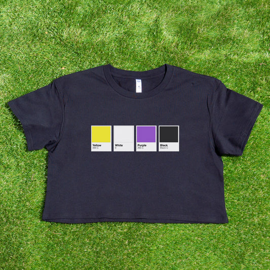 The Pantone pride flag crop tee, locally printed by Gay Skate, is a chic black top featuring durable prints with four color swatches on the front—yellow, white, purple, and black—each labeled with its name and CMYK code. Perfect for demonstrating support for a Trans and Queer Owned brand, this stylish tee is beautifully displayed on green grass.