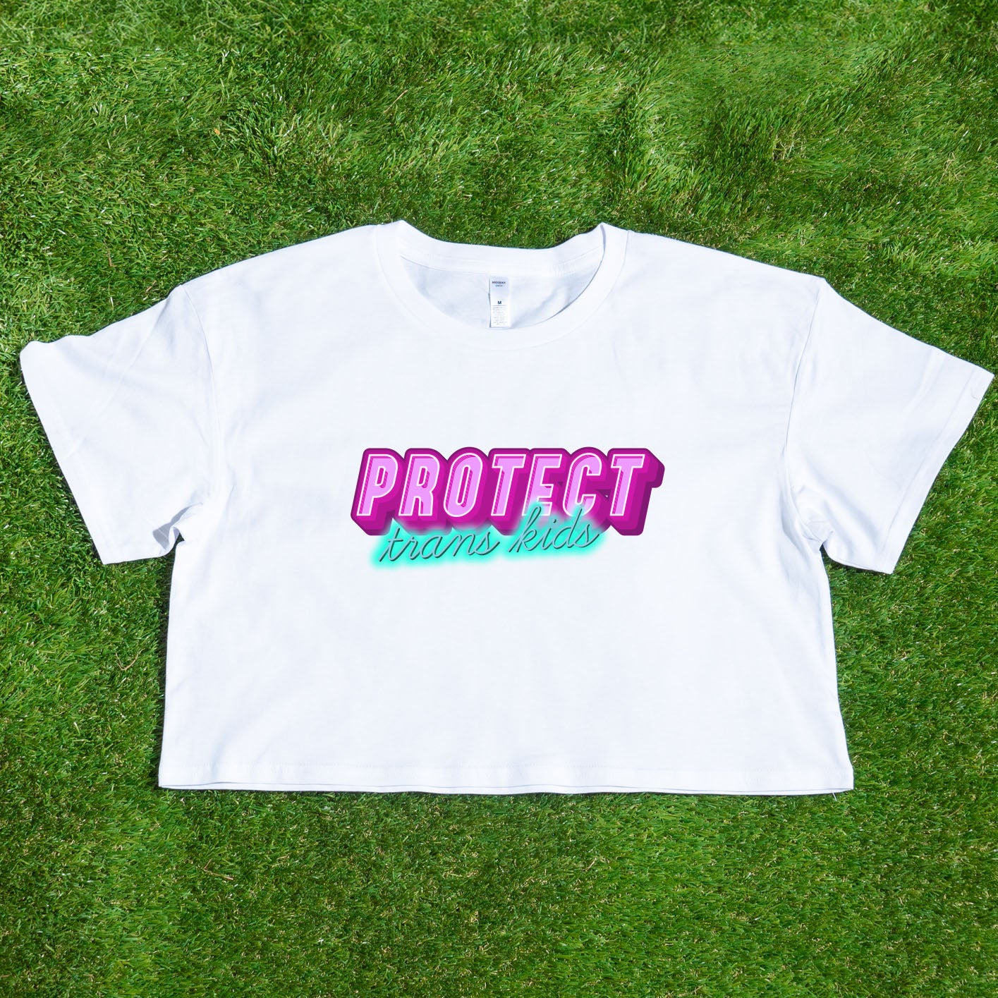 The Gay Skate's "Protect Trans Kids - original design - locally printed crop tee" is a black crop top t-shirt that proudly displays the text "PROTECT trans kids" in bold, vibrant pink and teal letters across the chest. The eye-catching font and incorporation of transgender pride flag colors make it a standout piece in queer skate and streetwear.