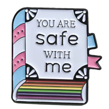 The "You Are Safe With Me" enamel badge by Gay Skate is a colorful pin shaped like a book, featuring the phrase on its cover. Its spine and edges have pastel stripes, celebrating rainbow pride.