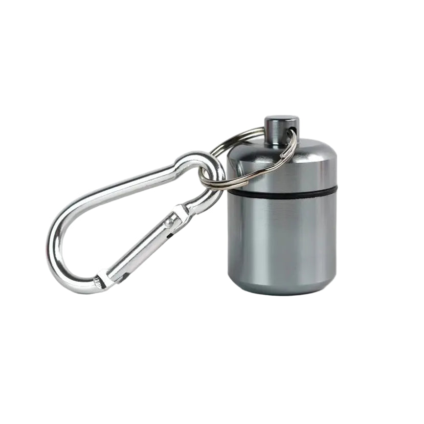 A small aluminium grey cylindrical container attached to a silver carabiner for storing medication