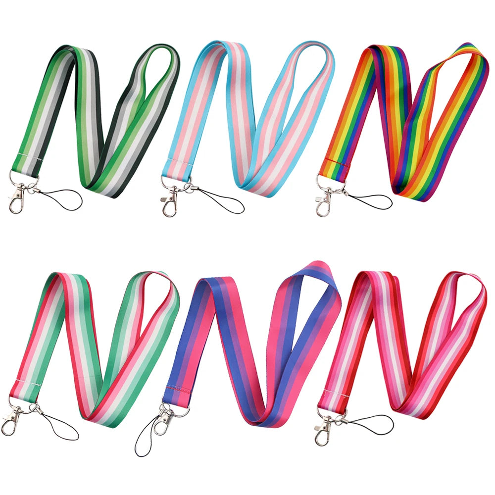 Six vibrant Pride Flag Lanyards from Gay Skate are displayed against a white background. Each practical neck strap showcases a distinctive design representing different pride flags: Rainbow, Trans, Non-Binary, Lesbian, Bisexual, Abrosexual/Abroromantic, and Aromantic. Every lanyard comes with a sturdy metal clip for securing keys or an ID.