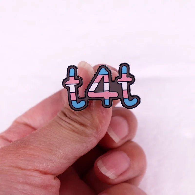 The Gay Skate Transgender T4T LGBTQ+ Enamel Pin proudly displays the term "t4t" with each letter and number filled in with the colors of the transgender pride flag: light blue, pink, and white. This stylish pin is a perfect accessory for showing solidarity and pride.