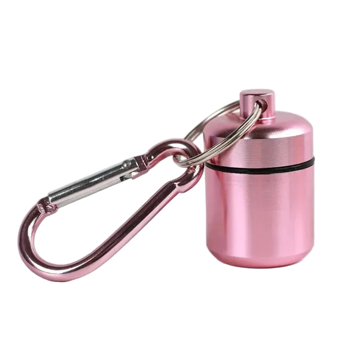 A small metallic pink cylindrical pill container with pink carabiner