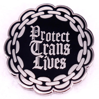 The Protect Trans Lives enamel pin by Gay Skate features bold Gothic-style lettering with a black badge and a white chain border.