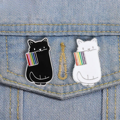 Two cat-shaped pins with rainbow flags on a denim background