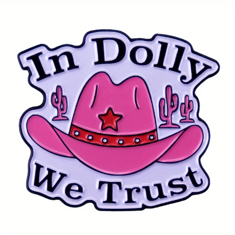 A pink cowgirl hat enamel pin called “In Dolly We Trust,” featuring a red star, cacti in the background, and the phrase “In Dolly We Trust” surrounding the hat.