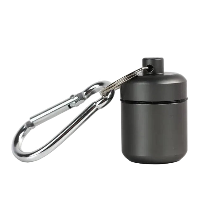 A small matte dark gray cylindrical  aluminium container with a silver carabiner attached