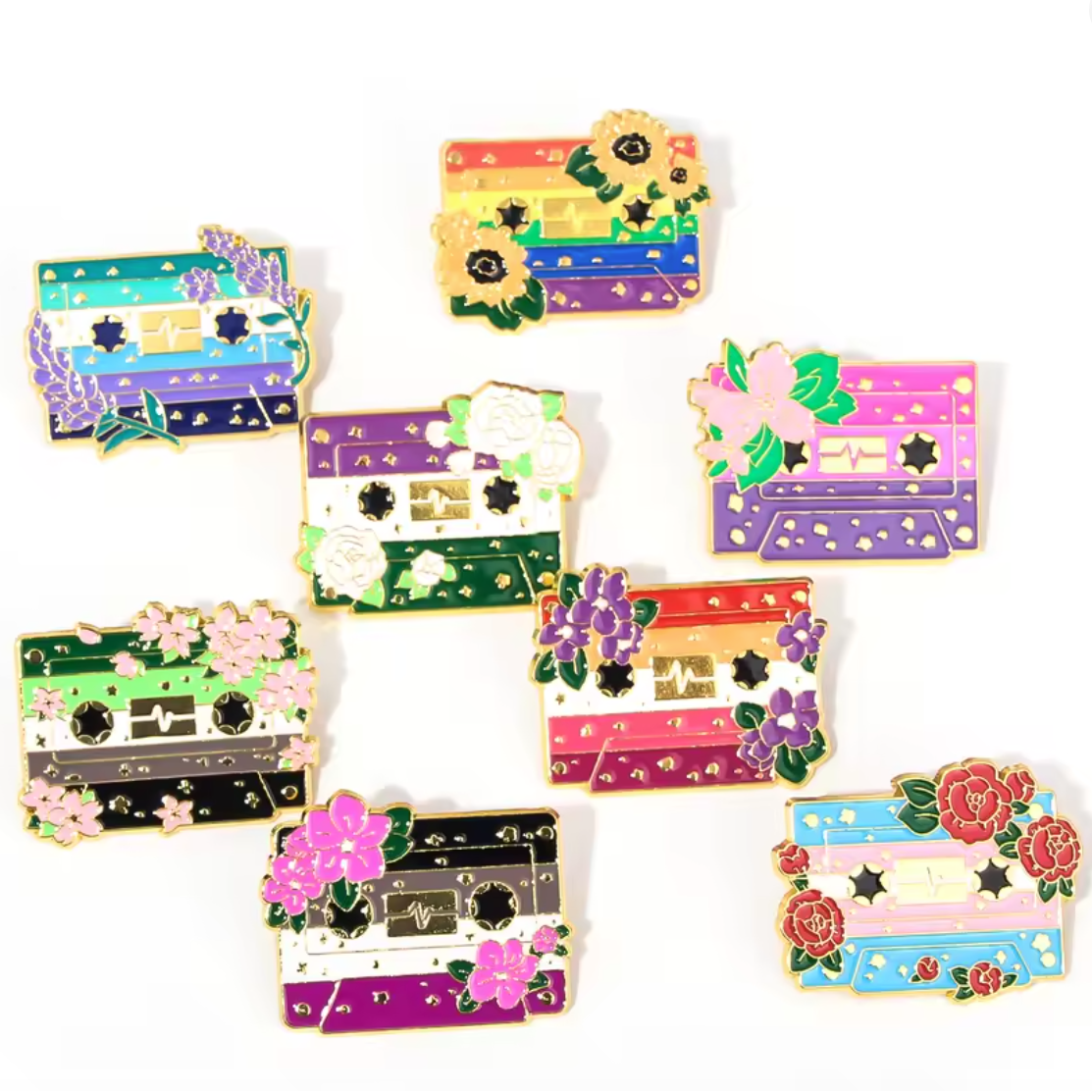 Colorful pride flag badges as cassette tape-shaped pins with floral decorative elements 