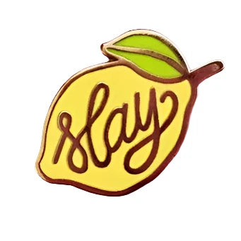 Sapphic lesbian themed badge featuring a lemon with gold font that says SLAY. Queer as lemons, slay all day lesbians.