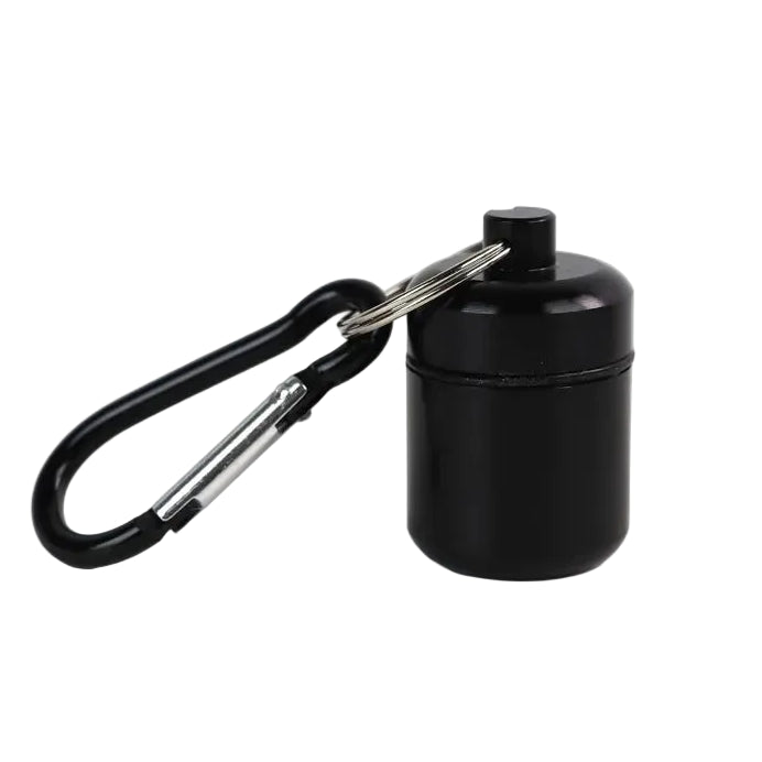 A small black waterproof cylindrical pill container with a screw-top lid, attached to a black carabiner via a small metal keys ring 