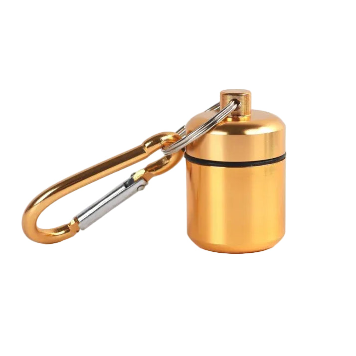 A small aluminium gold cylindrical pill container attached to a gold carabiner 